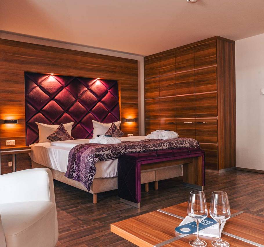 Doppelzimmer in der Ferienwohnung in Binz auf Rügen mit großem Doppelbett, lila Akzenten und Holzmöbeln.