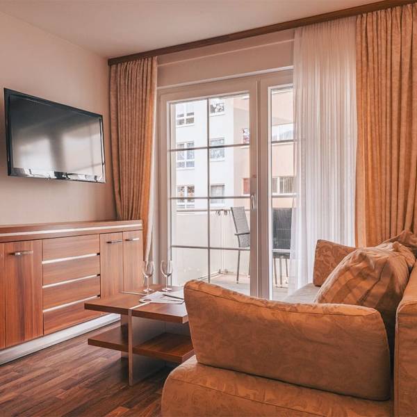 Living room in the apartment at Arkona Strandresidenzen Binz with sofa, TV, and balcony access