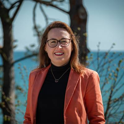 Portrait picture of management assistant Dorothee Schicht in front of the Baltic Sea, who helps with press and cooperation issues at Arkona Hotels.