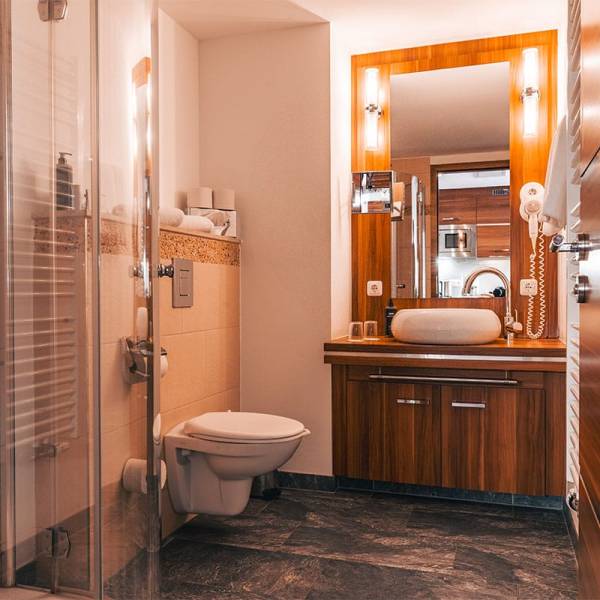 adezimmer im Deluxe Apartment der Arkona Strandresidenzen Binz mit Dusche, Waschtisch, Spiegel und Holzelementen
