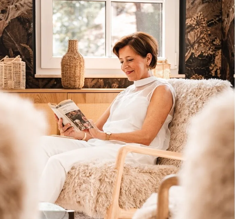 Woman relaxing and reading in a comfortable armchair at Rugard Strandhotel on Rügen
