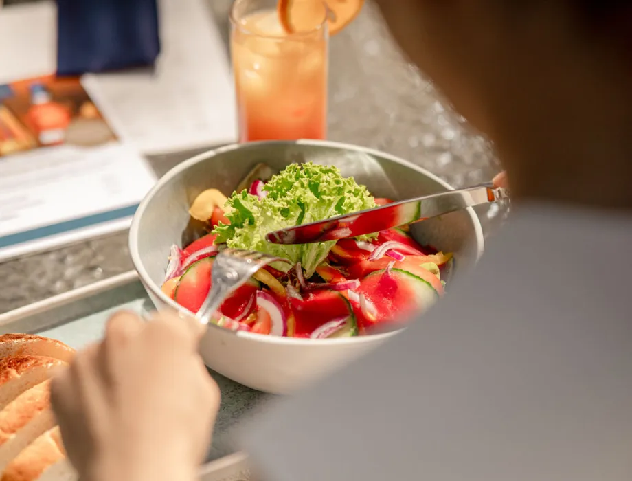 Woman on the terrace of Arkona Strandresidenzen in Binz – fresh salad with seasonal ingredients from the region