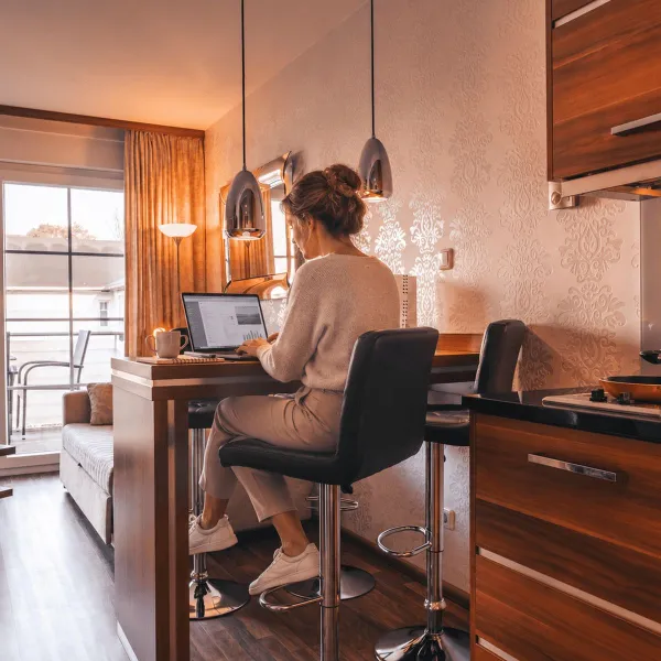 Frau arbeitet am Laptop am Küchentresen eines modernen Apartments der Strandresidenzen Binz.