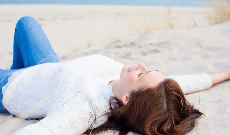 A woman lies on the beach in Binz with her arms outstretched, enjoying the Baltic Sea breeze.
