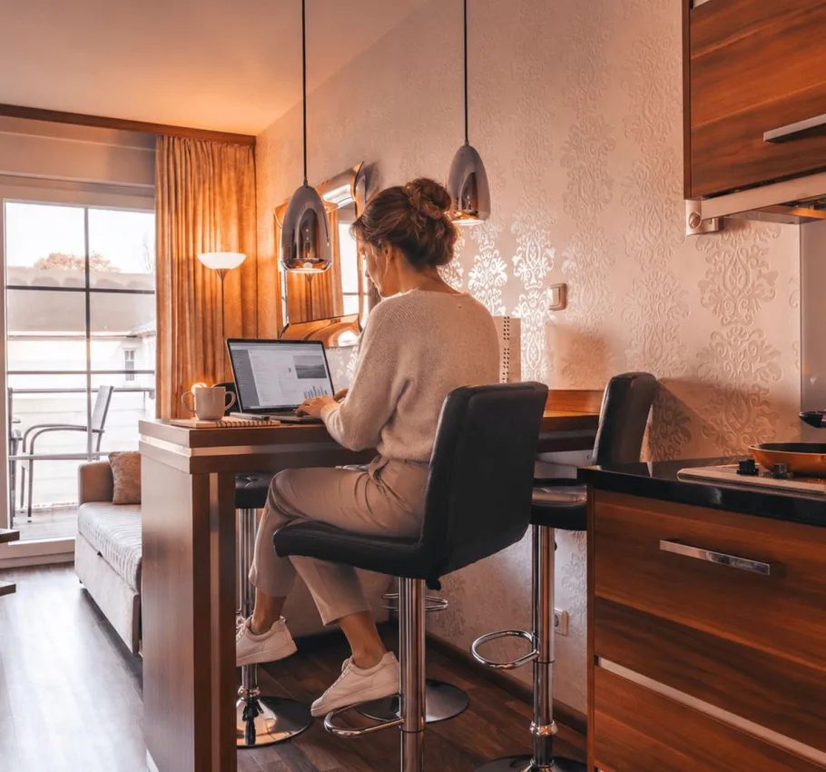 Woman working on a laptop at the kitchen counter in a modern apartment at Strandresidenzen Binz.